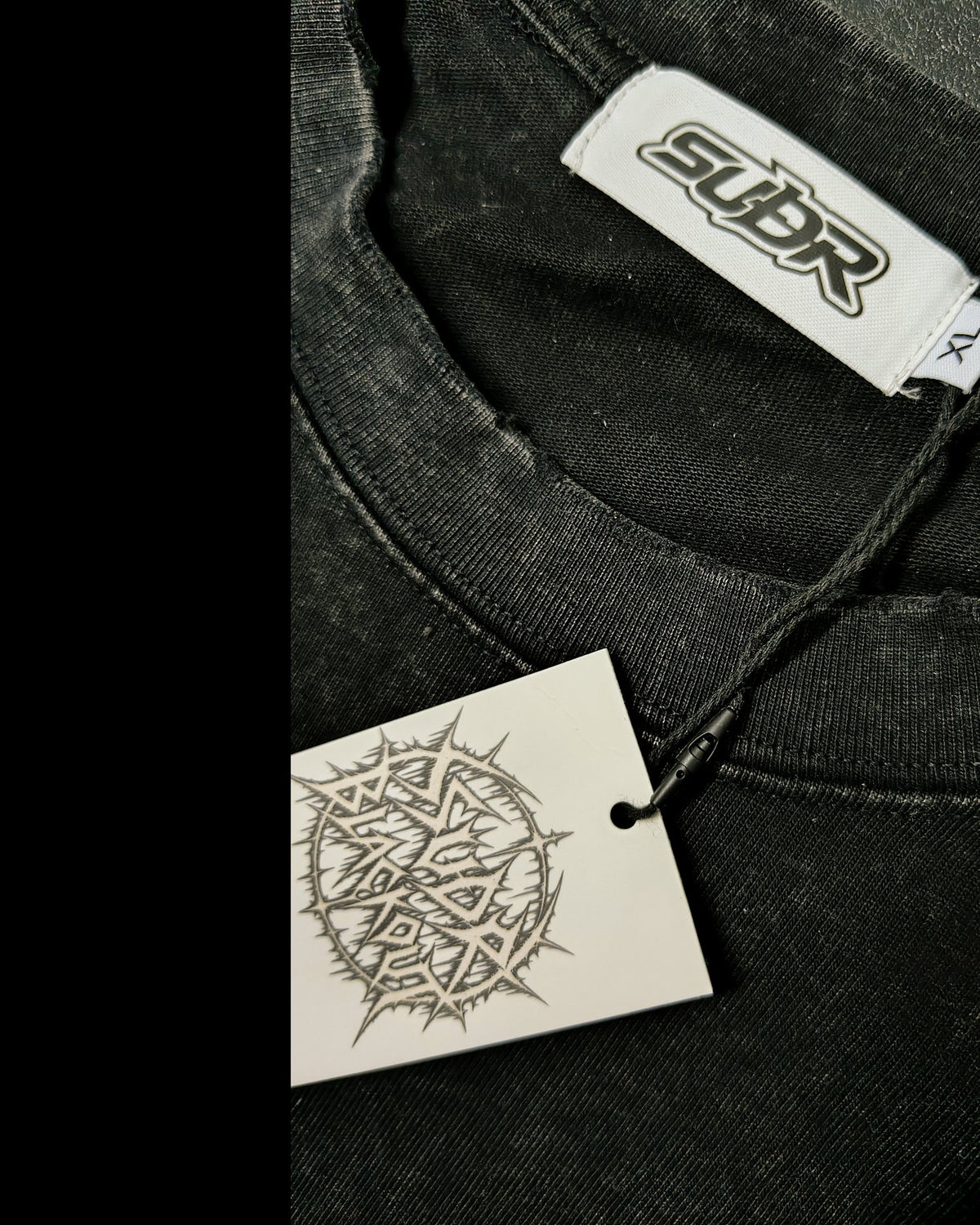BLACKOUT snow wash raw-hem boxy T-Shirt – Detail: SUÐR-Etikett im Nacken und Hangtag