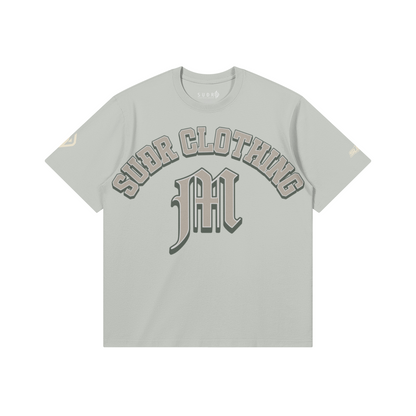 SUÐR M Shirt – Shirt in Light Gray, Vorderseite mit SUÐR CLOTHING im Bogen, darunter das M in Blackletter, Emblem und SUÐR-Schriftzug auf den Ärmeln, liegend