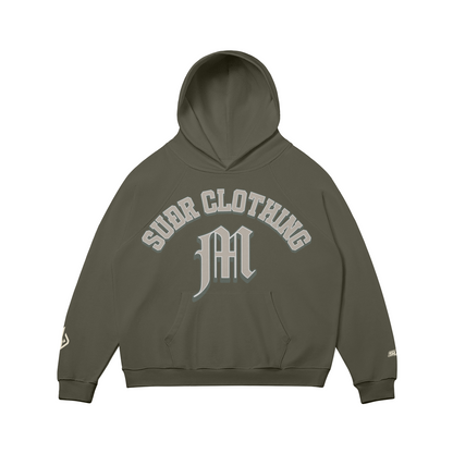 SUÐR M Hoodie – Hoodie in Charcoal Grey, Vorderseite mit SUÐR CLOTHING im Bogen, darunter das M in Blackletter über der Kängurutasche, Emblem und SUÐR-Schriftzug auf den Ärmeln, liegend